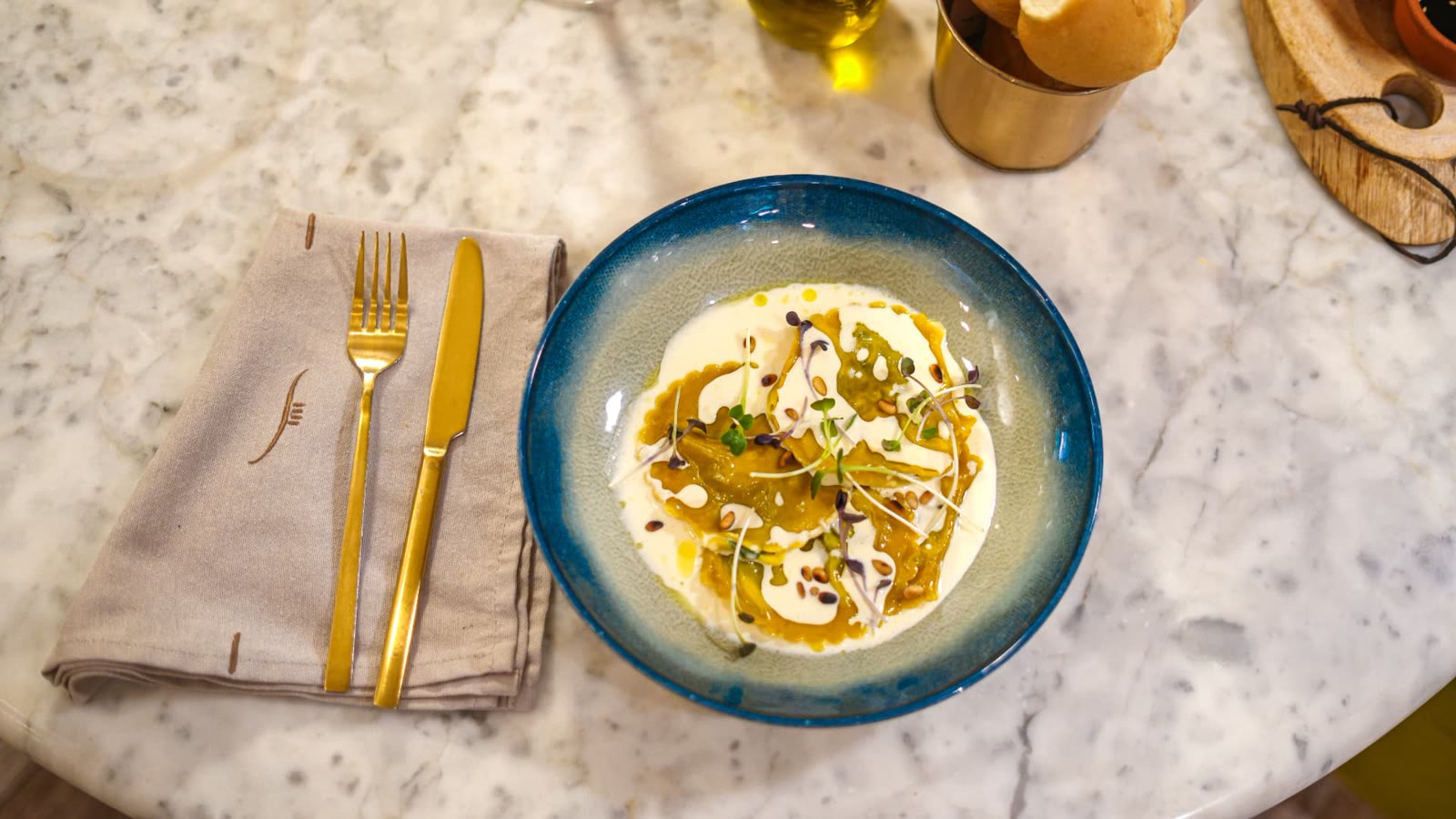 Assiette de raviolis à la crème et pignons, couverts dorés sur marbre