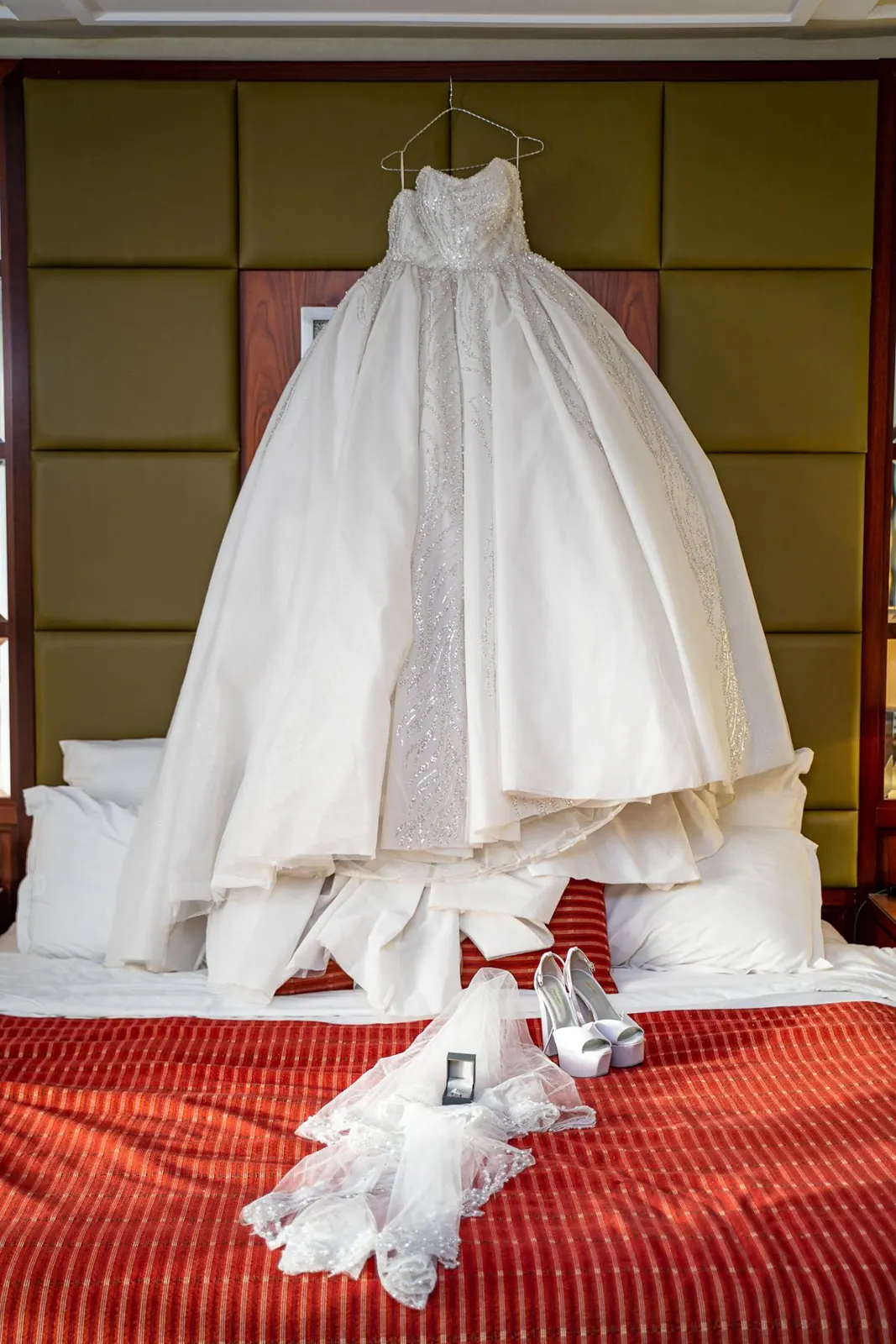 Robe de mariée suspendue au-dessus du lit, voile et chaussures