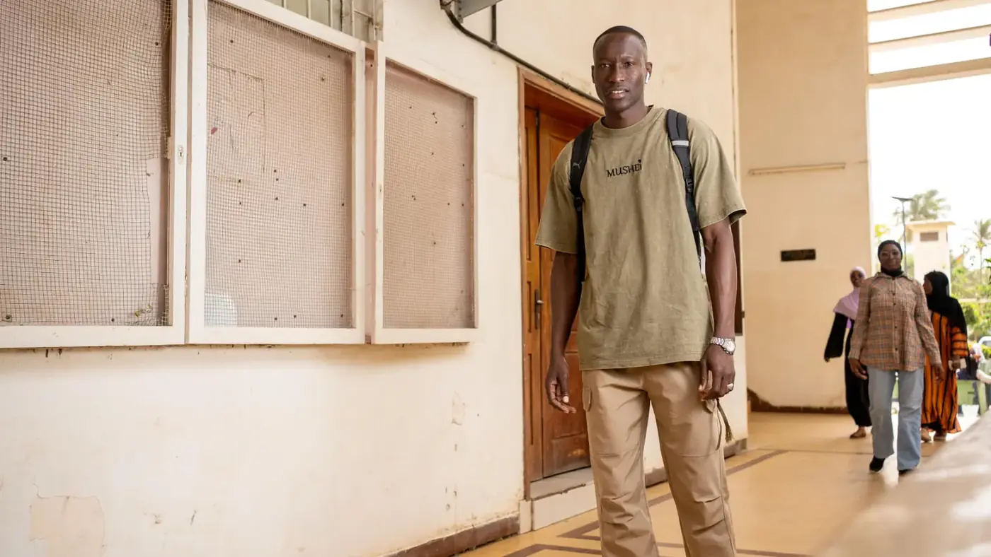 Étudiant avec son sac à dos dans un couloir d’établissement, portrait KARIMKO pour le CETUD.