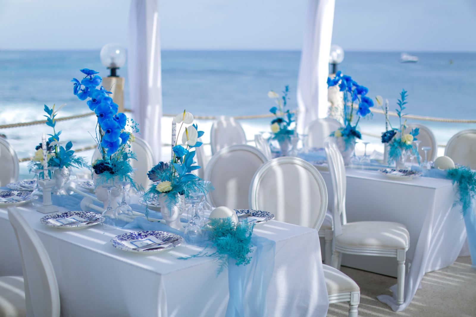 Tables dressées en bleu et blanc face à l'océan