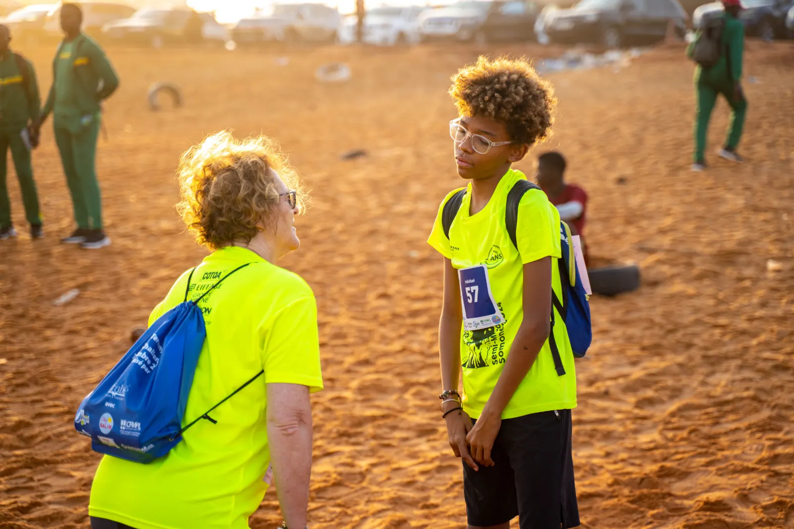Échange entre une bénévole et un jeune coureur au lever du soleil