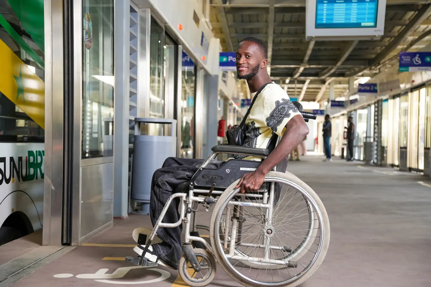 Homme en fauteuil roulant sur un quai de station BRT, photographié par KARIMKO pour le CETUD.