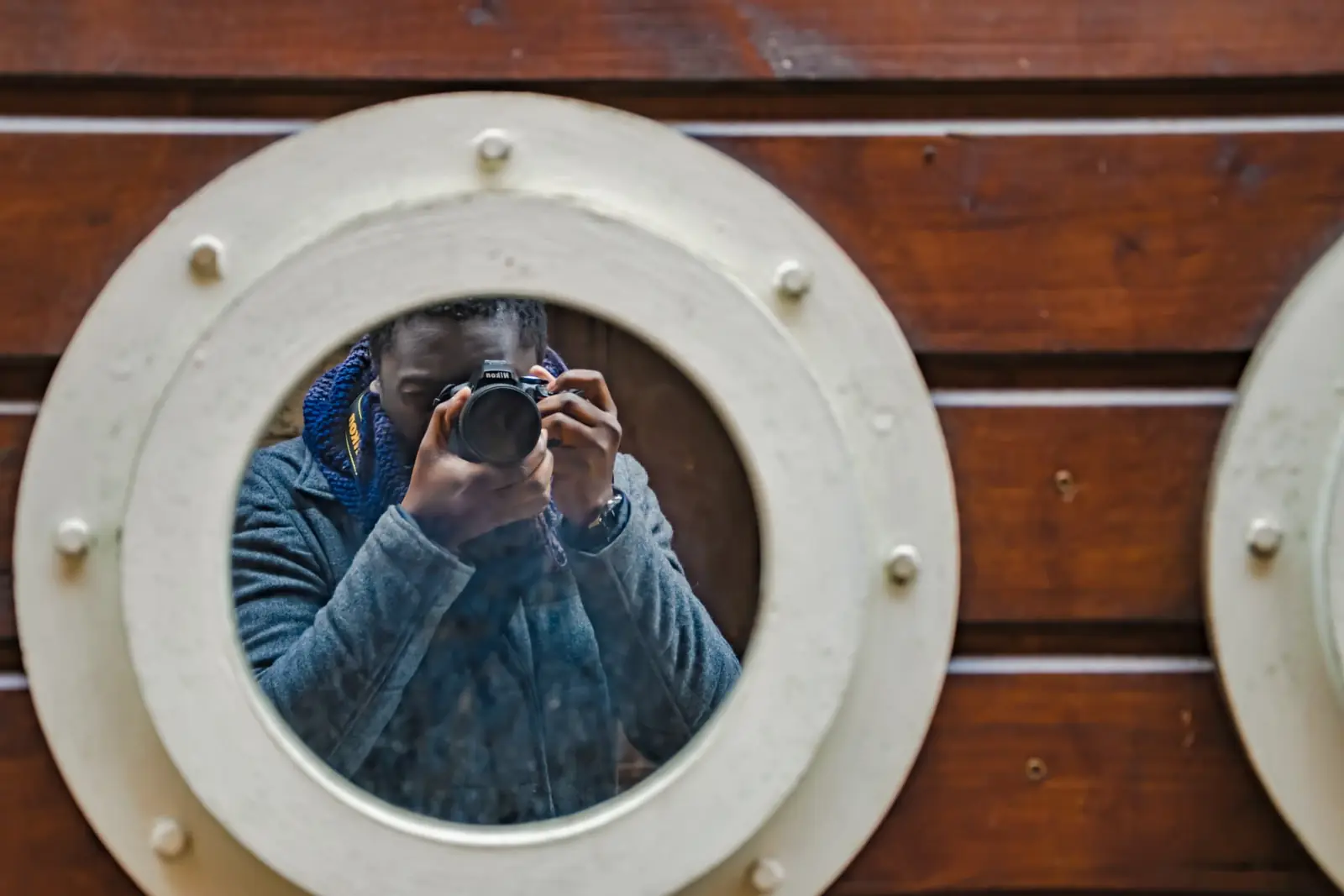 Autoportrait d'Abdou Karim Gaye, appareil photo en main, dans un hublot