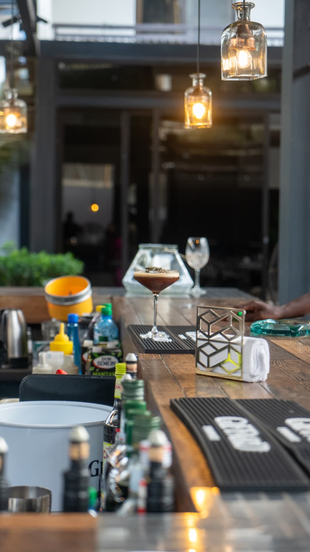 Comptoir du bar Alkimia avec un cocktail au café sous les suspensions