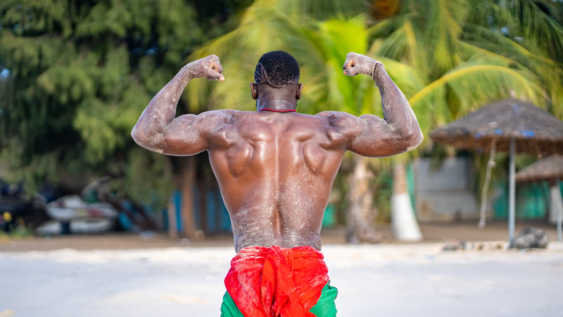Lutteur de dos, bras fléchis, sur la plage