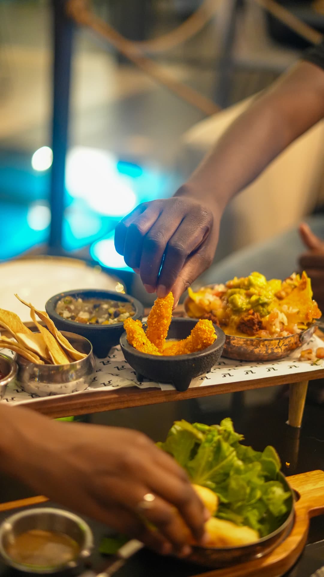 Main piochant un bâtonnet pané près des nachos