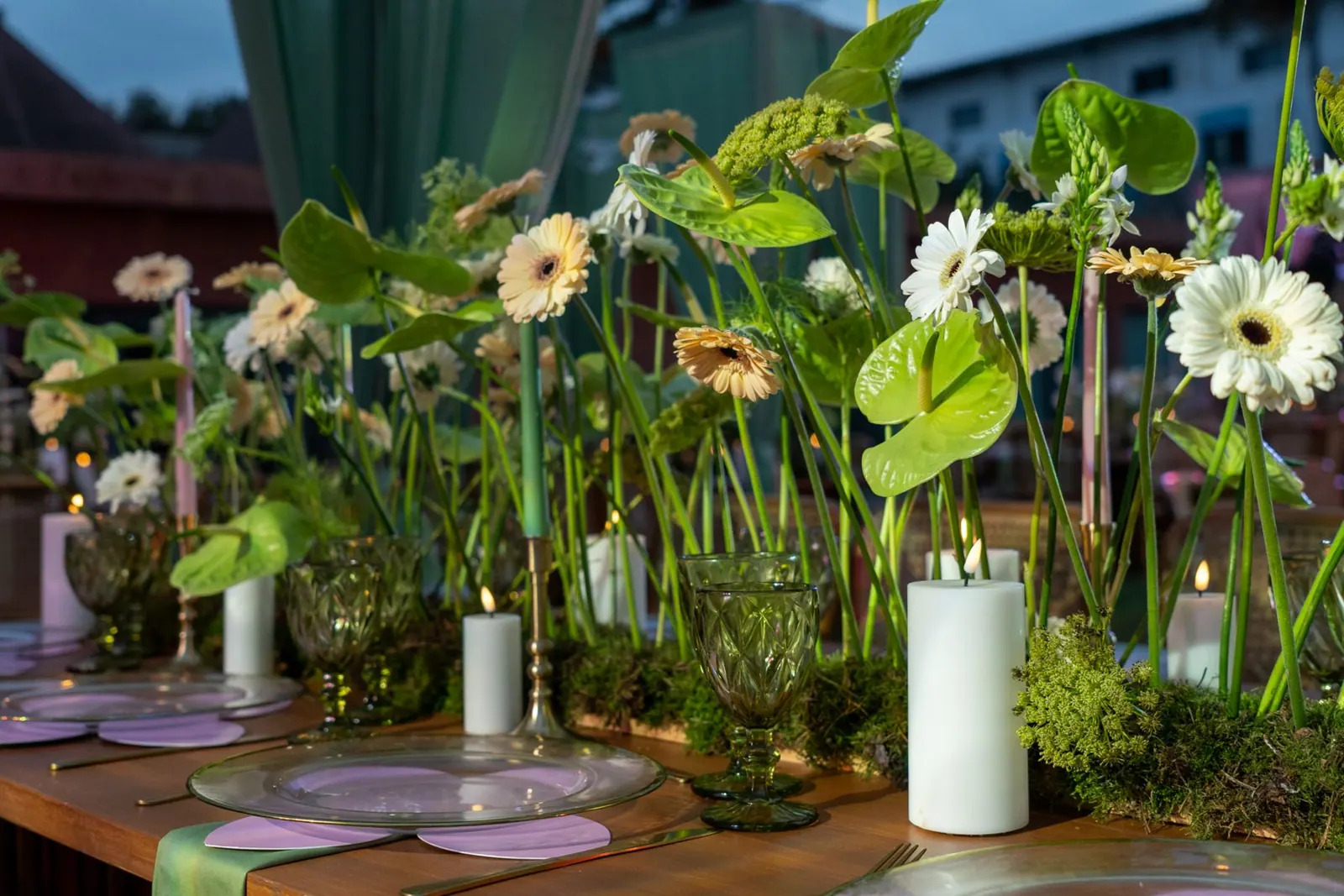 Table fleurie de gerberas, bougies et verres verts