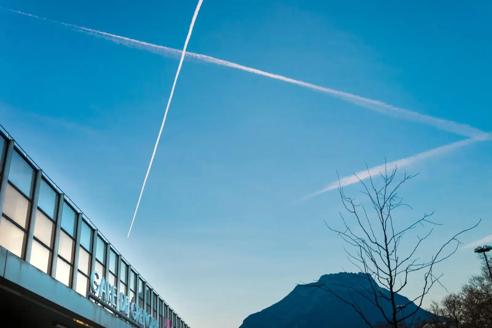Traînées d'avions dans le ciel bleu au-dessus de la gare de Grenoble