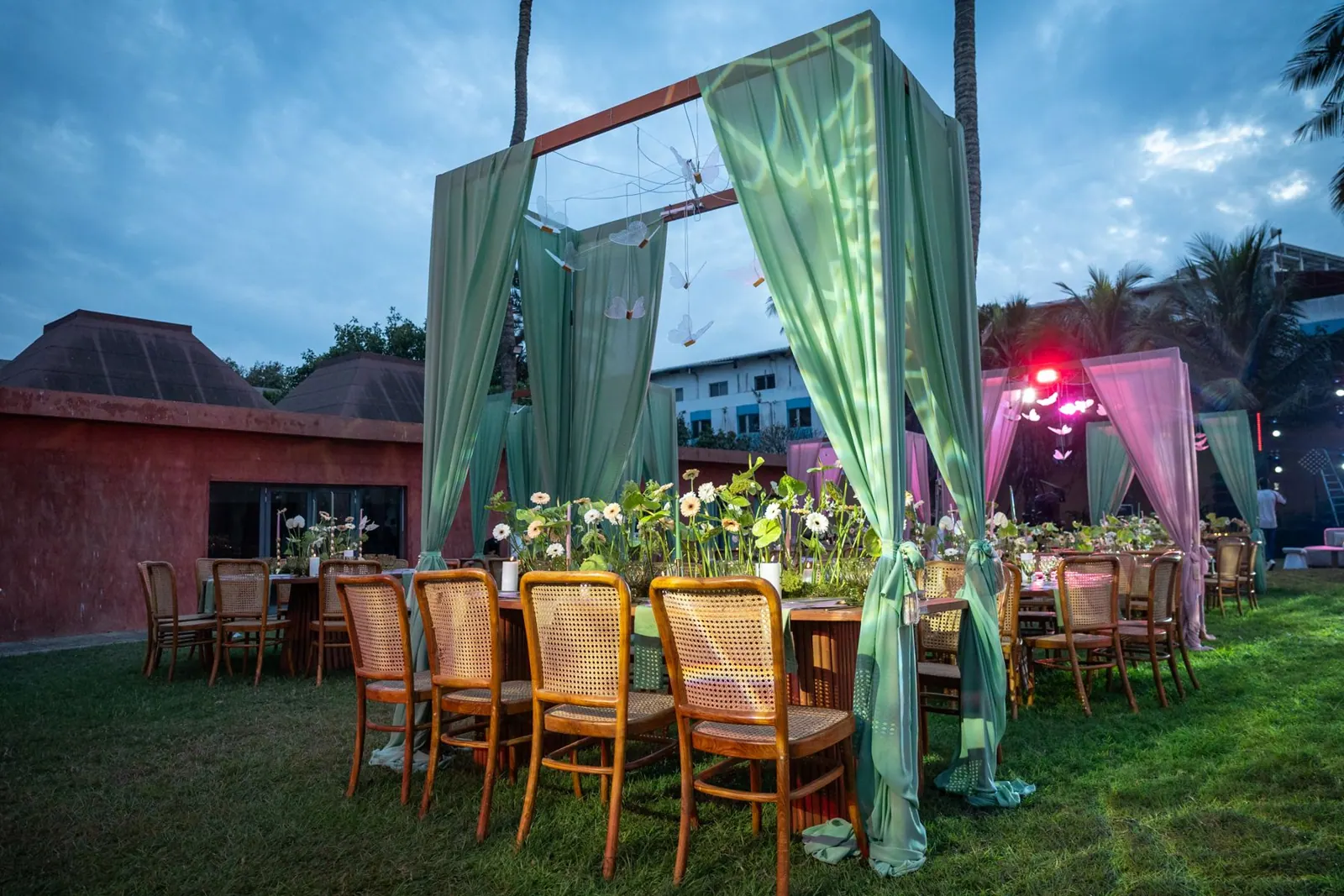 Pergola en tissu vert d'eau dressée sur la pelouse, table fleurie