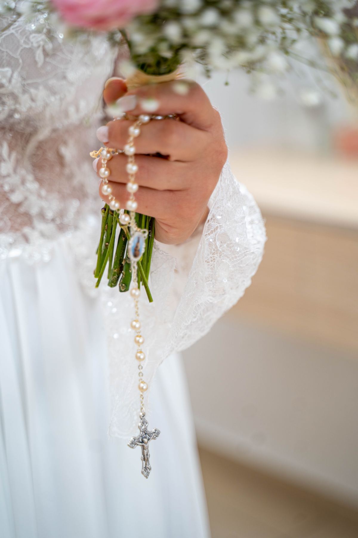 La mariée tient son bouquet orné d'un chapelet en perles