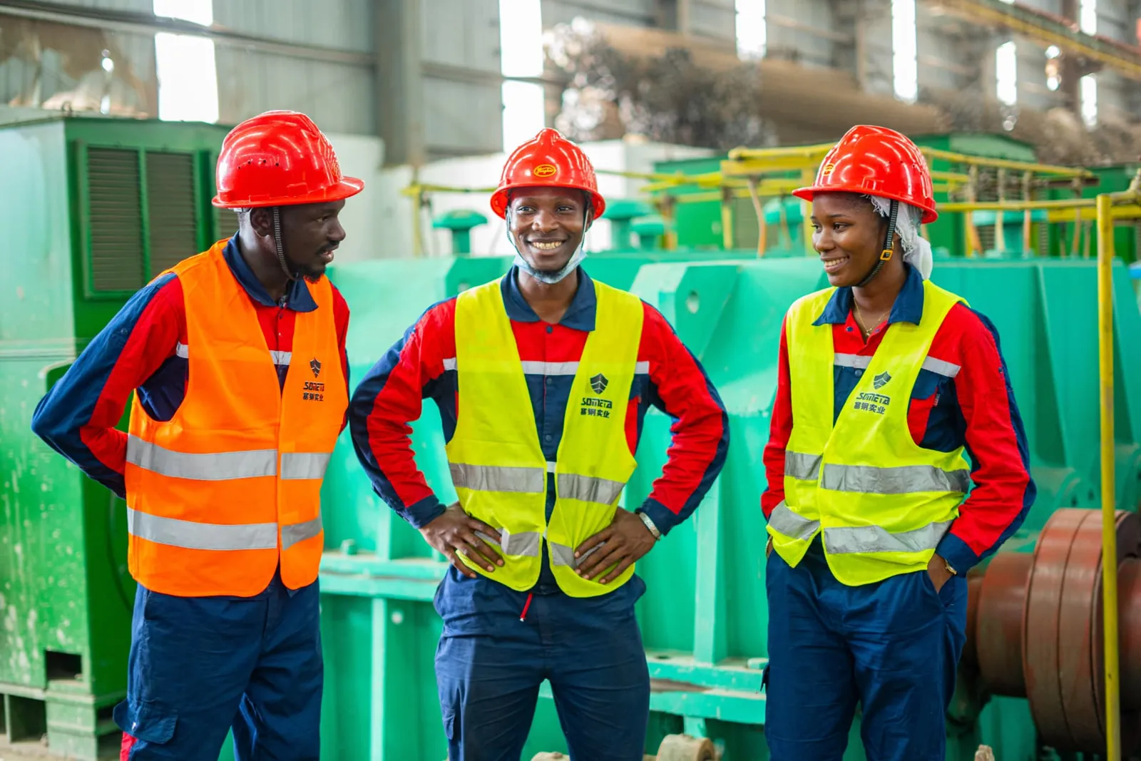 Trois collaborateurs souriants devant les machines