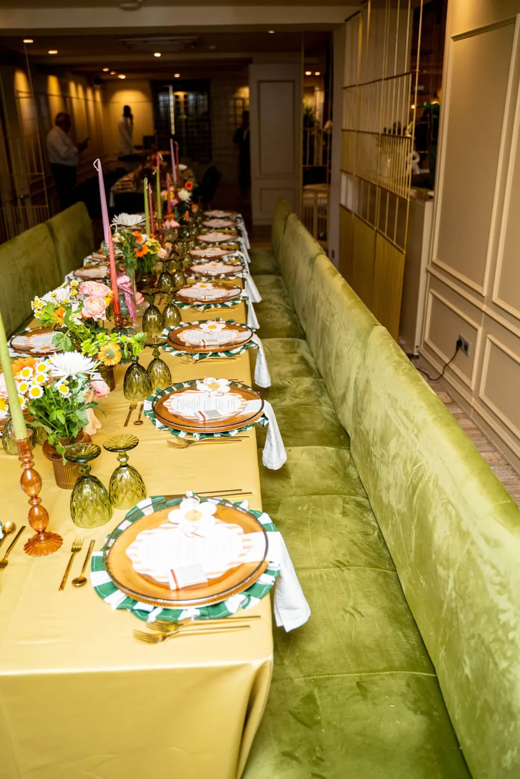 Longue table fleurie dans un salon aux banquettes vertes