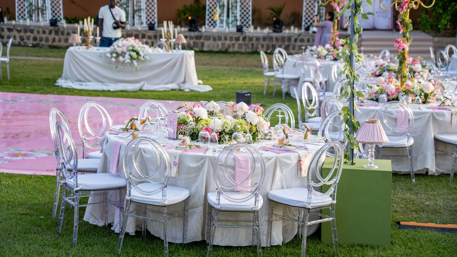 Tables de réception dressées sur la pelouse, chaises transparentes