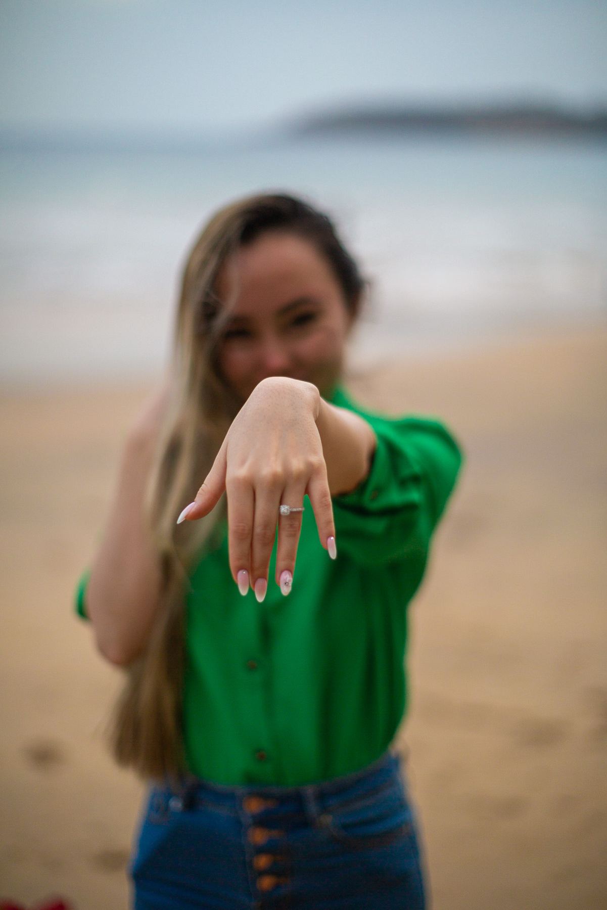 La future mariée montre sa bague de fiançailles sur la plage